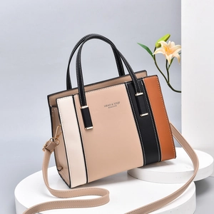 Chic color-block handbag with beige and black geometric PU leather on a display stand