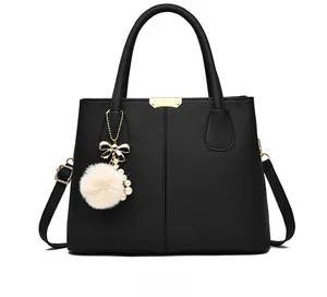 Front view of black lychee leather tote bag with gold hardware and plush charm