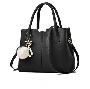 Detailed side view of black pebble leather handbag with faux fur pearl charm