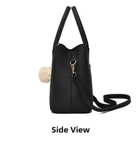 Side view of black lychee-textured tote bag with plush ball and gold-tone hardware