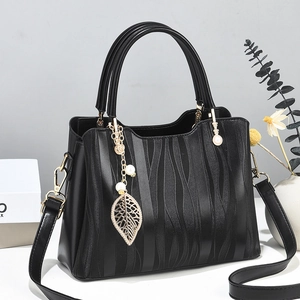Elegant black wave-patterned handbag with golden leaf pearl pendant and crossbody strap