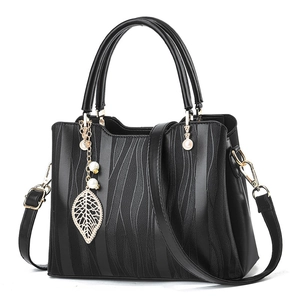 Elegant black faux leather handbag with vertical ripple pattern and golden leaf charm