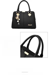 Close-up of black litchi grain leather handbag with golden hardware and floral charm