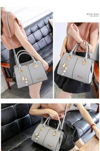 Detail of grey lychee textured faux leather handbag with gold hardware and floral charm