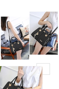 Detail of black faux leather tote bag with gold hardware and floral charm accessory