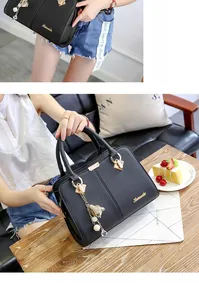 Detail of black lychee grain leather tote bag with gold logo and tassel accent