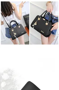 Detail of black pebbled leather handbag with gold buckle and floral pearl charm