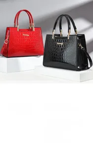 Detail of glossy crocodile pattern patent leather handbags with metallic brand logo