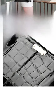 Detail of glossy crocodile embossed leather handbag with light gold metallic hardware