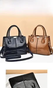 Detail view of glossy crocodile pattern handbags in black and brown with sleek handles