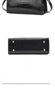 Detail view of the black crocodile pattern handbag back and golden protective metal feet