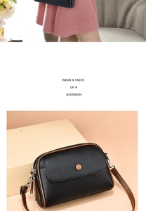 Detail view of black litchi grain crossbody bag with brown trim and round decorative buckle