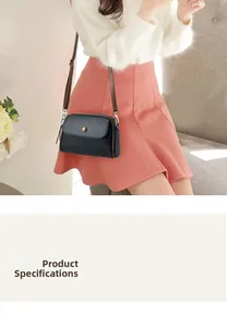 Detail of black crossbody bag featuring pebble leather texture and brown button closure