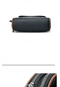 Detail of black lychee grain leather crossbody bag with brown edges and silver zipper