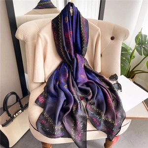 Detailed close-up of a long silk scarf with blue gradient tones and paisley patterns