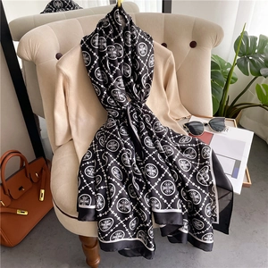 Close-up of luxury silk scarf with black and white cross patterns on a beige sofa