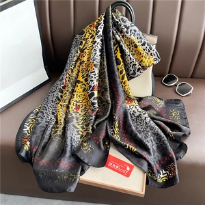 Luxurious leopard print silk scarf draped over a leather bag in a high-end fashion setting