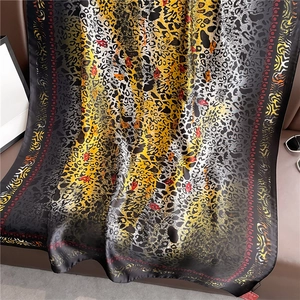 Luxurious leopard and paisley print oversized scarf draped on a leather sofa