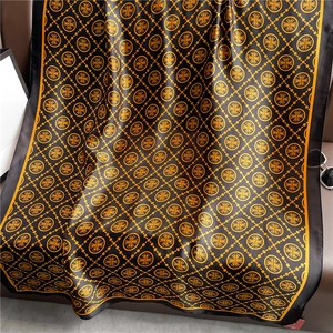Luxurious black and orange plaid scarf with heraldic patterns displayed on a leather sofa