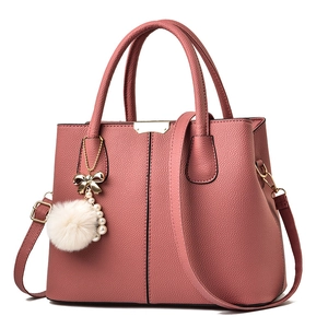 Sac à main rose foncé en cuir grainé avec détails dorés et pompon blanc décoratif