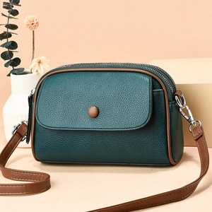 Mini green pebbled leather crossbody bag with brown trim and dual zipper design