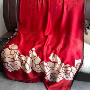 Detail of red and cream luxury silk scarf with floral patterns on a leather chair