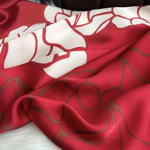 Detailed view of luxury red floral silk scarf showing fabric texture and glossy finish