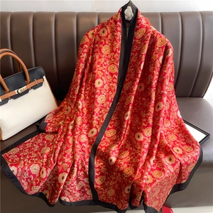 Detail of red silk scarf with vintage gold floral patterns and black border
