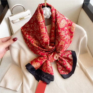 Detail of red silk scarf with golden floral paisley patterns and black wide border
