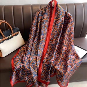 Detail of luxury silk scarf with blue floral patterns and elegant red border draping