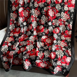 Détail d'un foulard en soie avec roses rouges et motif papillon sur tissu noir haut de gamme