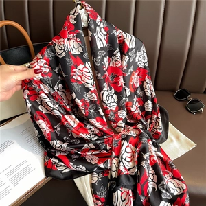 Gros plan d'un grand châle en soie à motif floral drapé élégamment sur un sac en cuir