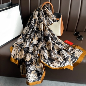 Écharpe de luxe en soie à motif floral et papillon avec bordure jaune sur canapé