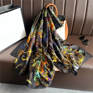 Close-up of luxury silky paisley scarf with colorful floral patterns on a handbag