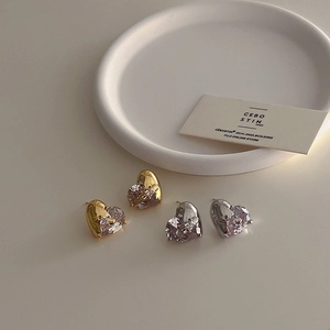 Detail of heart-shaped earrings with gold and silver plating and clear cubic zirconia