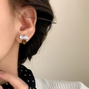 Retro zircon bow earrings with tiger eye stone pendant shown on model's ear