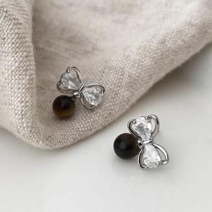 Detail of vintage zircon bow earrings featuring a tiger eye stone bead drop