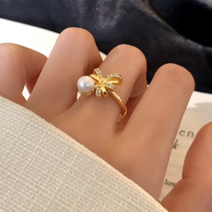 Elegant gold bow ring with micro-set zircons and white pearl on a model's finger