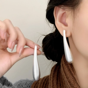 Elegant silver matte brushed teardrop long earrings worn by a model in a side view