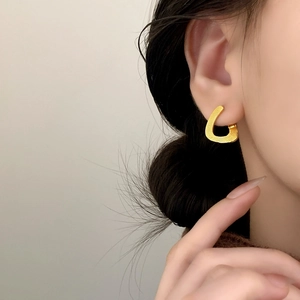 Minimalist golden teardrop earrings with textured linear finish on a female model