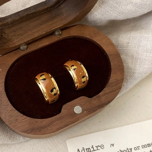 Close-up of leopard print enamel C-shape earrings inside a vintage velvet jewelry box