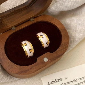 Detail of leopard print enamel hoop earrings inside a premium wooden jewelry box
