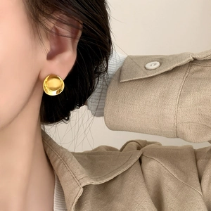 Minimalist brushed gold disc stud earrings with polished edges worn by a model