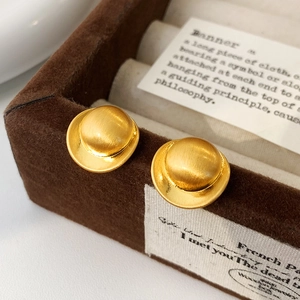 Detailed close-up of matte gold dome stud earrings on dark brown velvet box