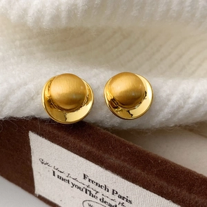 Macro shot of gold stud earrings featuring a matte dome center and polished outer ring