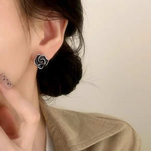 Close-up of black enamel rose earrings on ear showing refined vintage floral style