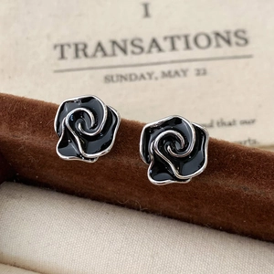 Macro shot of retro black enamel rose earrings with silver edges on a jewelry card