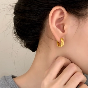 Modern gold irregular wrinkled hoop earrings with a brushed finish on model