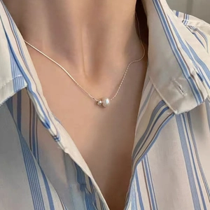 Minimalist silver freshwater pearl necklace worn over a blue striped shirt for elegant style
