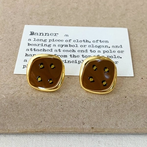 Close-up of vintage square stud earrings with gold edges and brown leopard pattern